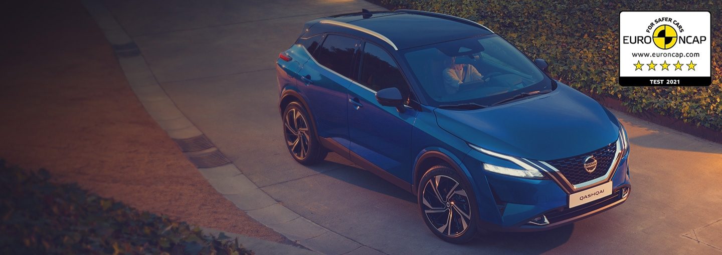 NISSAN QASHQAI Visia vor einem Wohnhaus mit einer Stadt und untergehender Sonne im Hintergrund