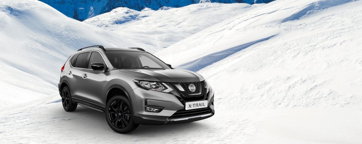Grauer NISSAN X-TRAIL in Winterlandschaft mit Schnee