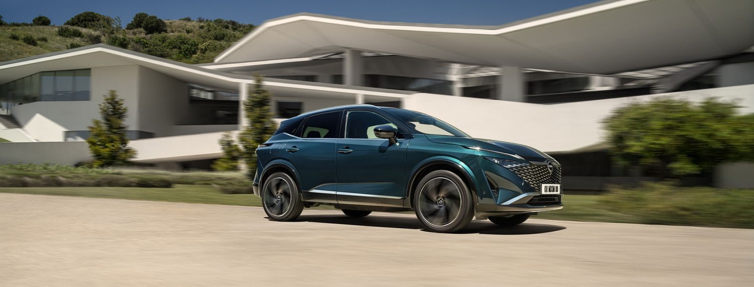Nissan Qashqai de profil roulant devant une maison en plein soleil