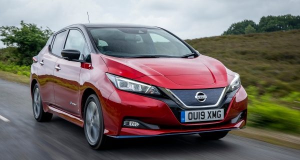The electric nissan leaf driving down a green country road