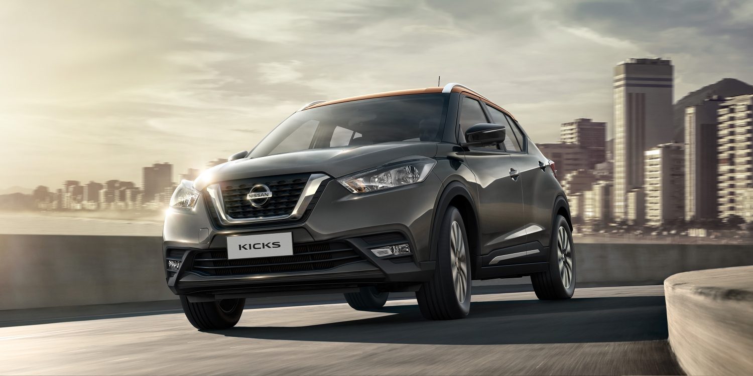 Նարնջագույն և մոխրագույն Nissan Kicks-ի արտաքին տեսքը մայրուղու մերձատար ճանապարհին