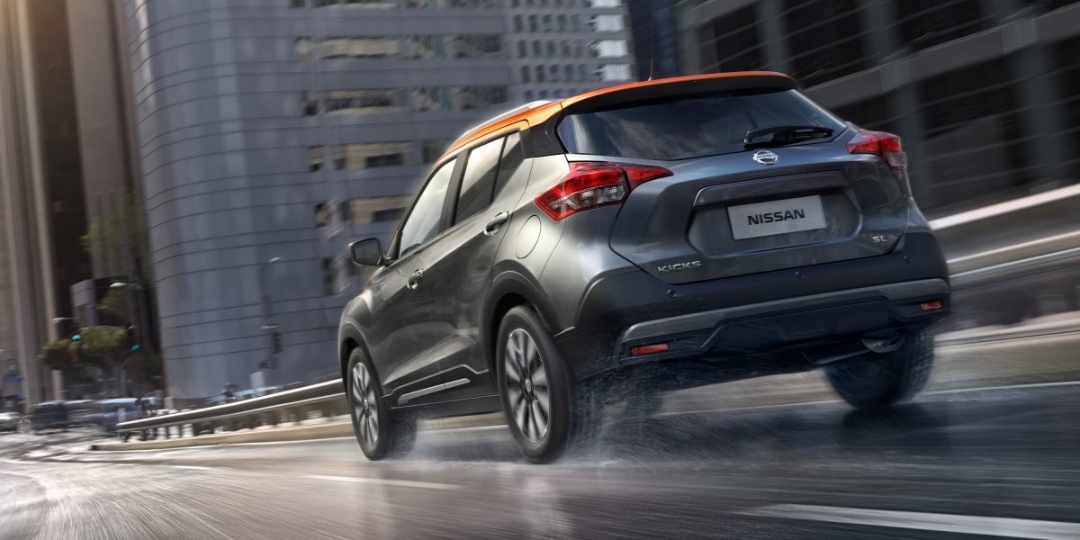 Նարնջագույն և մոխրագույն Nissan Kicks-ի արտաքին տեսքը մայրուղու մերձատար ճանապարհին