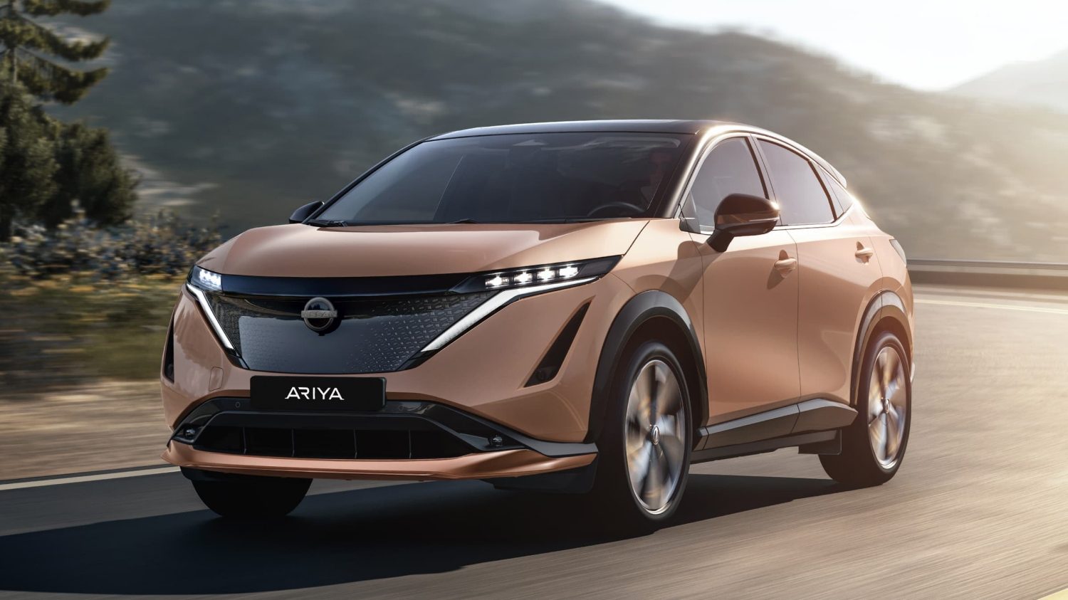 Nissan ARIYA vor einem Wohnhaus mit einer Stadt unter untergehender Sonne im Hintergrund