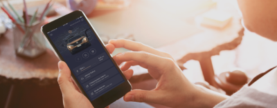 A hand holding a smartphone, showing the NissanConnect Services app.