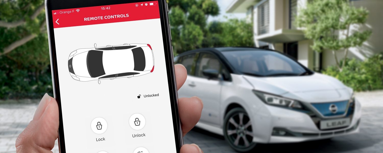 Älypuhelin, jossa LEAF-ikkuna, ja taustalla Nissan LEAF
