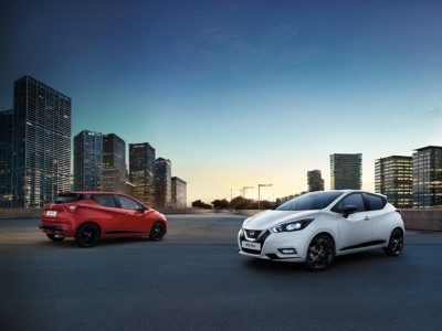 Sarkana un balta Nissan MICRA pilsētā.