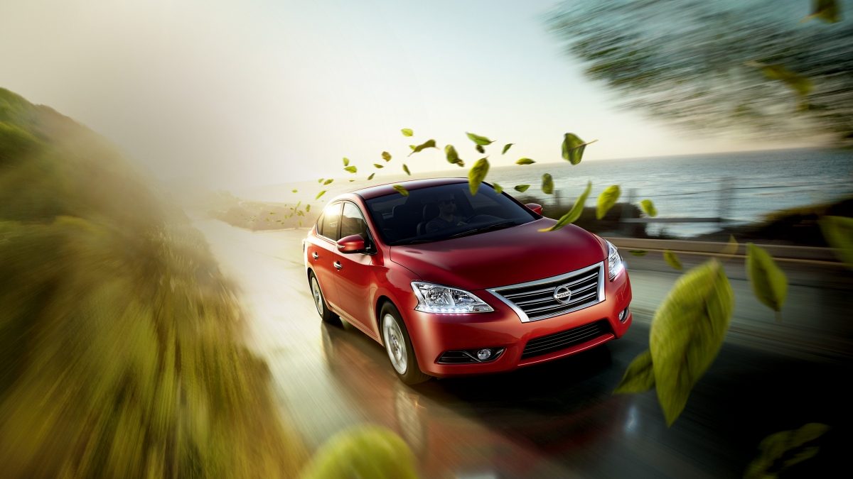 Red Nissan Sentra driving with leaves coming down
