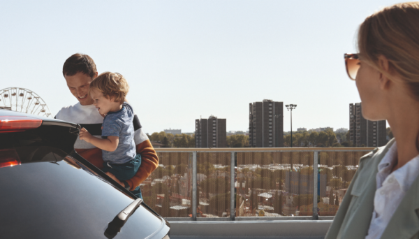 Ein Vater platziert sein Kind im Auto und die Mutter schaut zu.