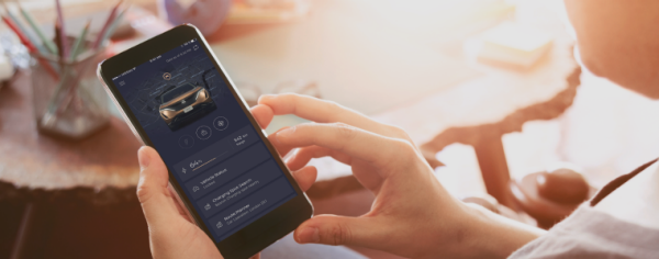 Eine Hand hält ein Smartphone, auf dem die NissanConnect Services App zu sehen ist.