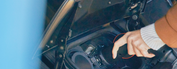 Eine Hand verbindet ein Ladekabel mit einem Elektrofahrzeug.