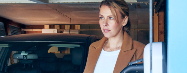 Eine Frau lädt ihr Auto an einer Wallbox.