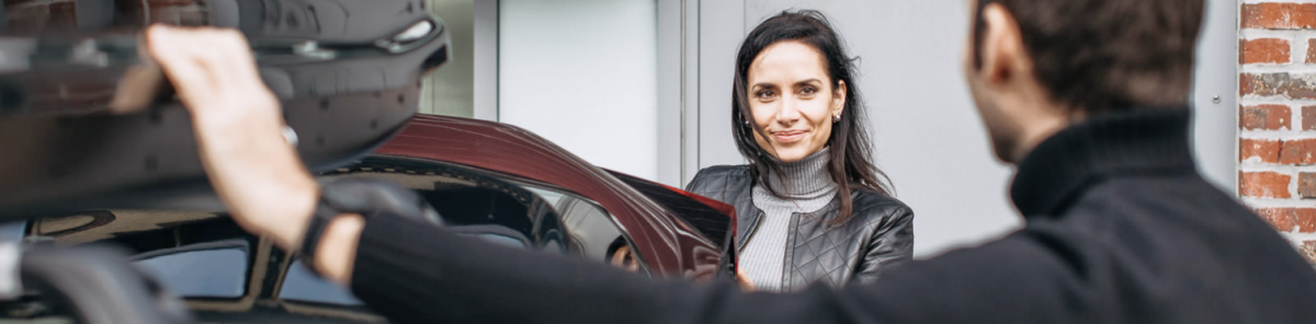 A woman smiles at her husband as he adjusts the roof rack.