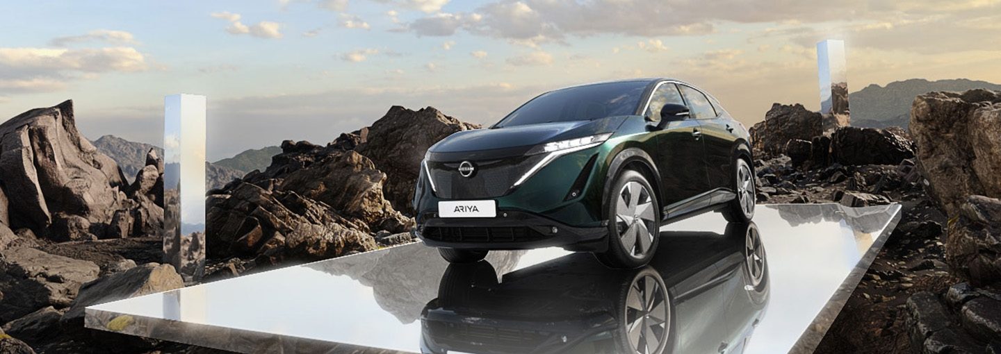 Nissan Ariya parkiran na zrcalnoj platformi u planinskom krajoliku.