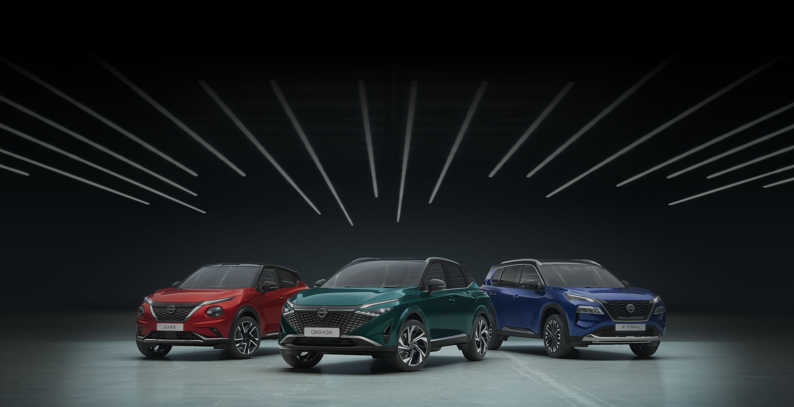 Rdeči Nissan Juke, zeleni Nissan Qashqai in moder Nissan X-Trail z ozadjem v sivi barvi.