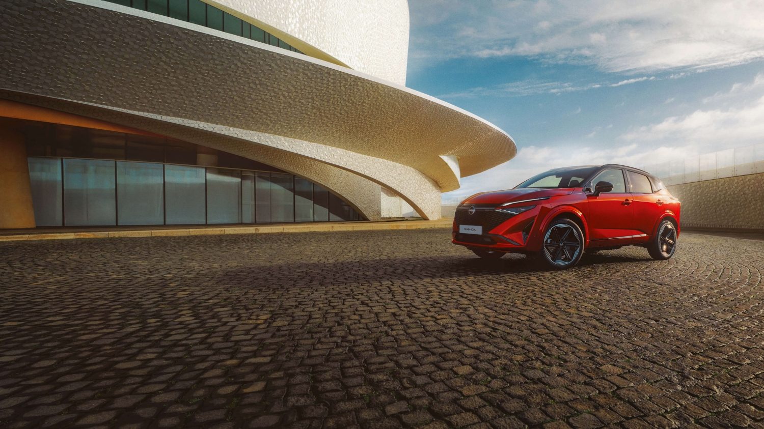 Nissan Qashqai e-Power, hibridni SUV, statičan prikaz sprijeda iz kuta 3/4 ispred zgrade.