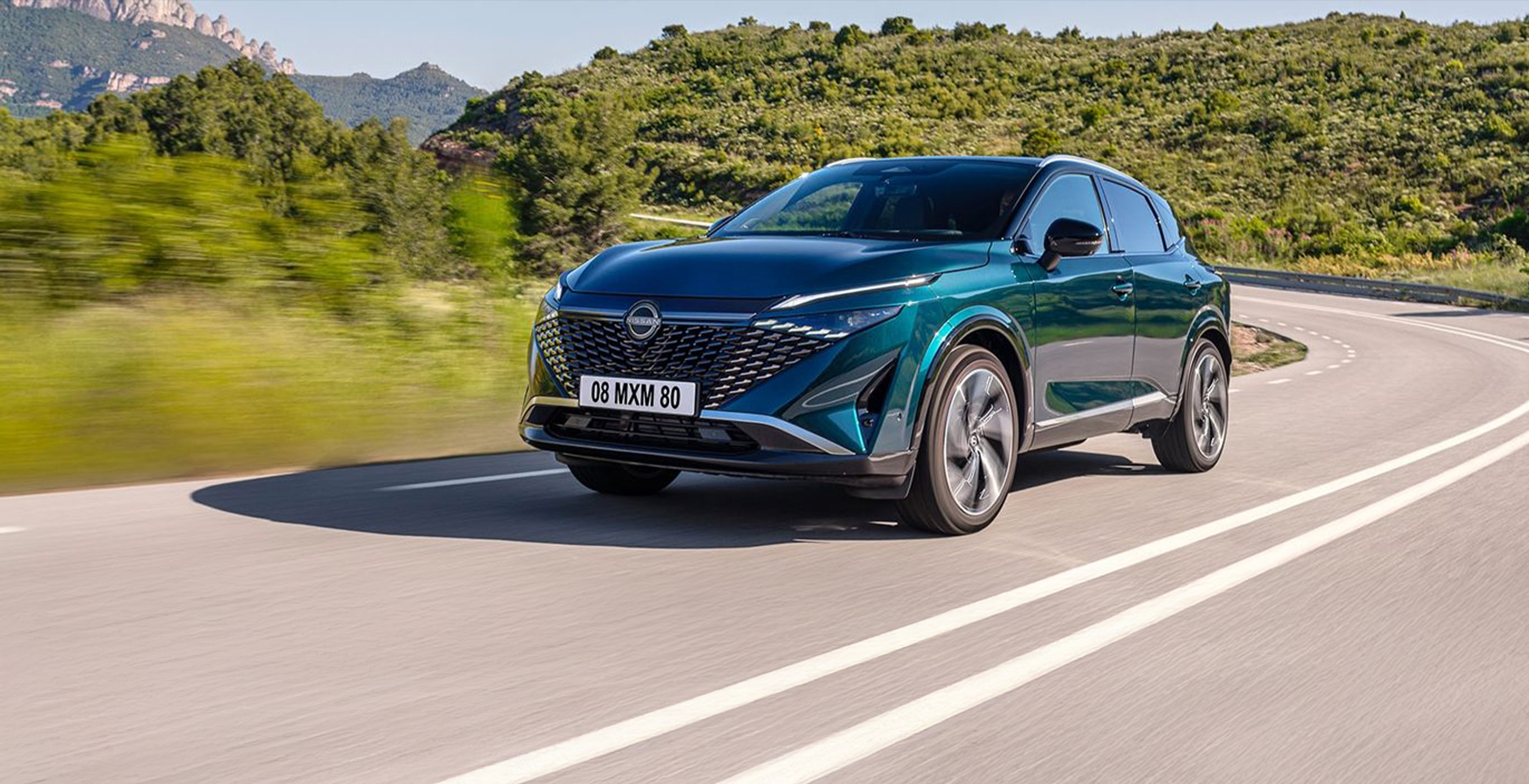 Zeleni Nissan Qashqai med vožnjo v zeleni pokrajni.