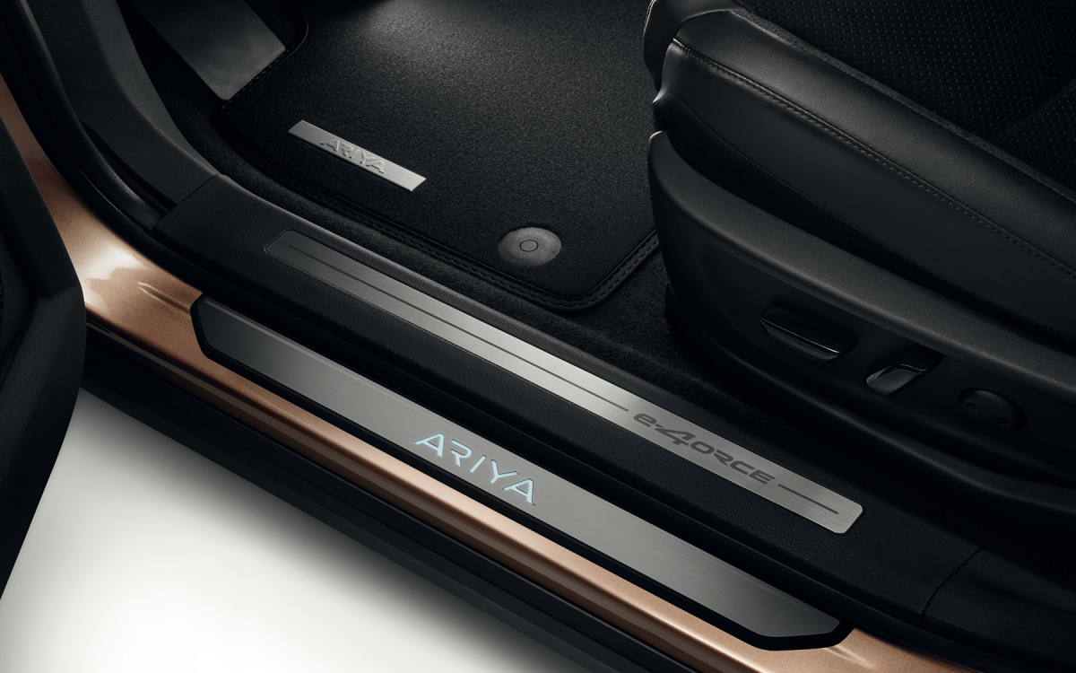 Schwarze beleuchtete Einstiegsleiste mit ARIYA Schriftzug an einem Nissan ARIYA montiert.