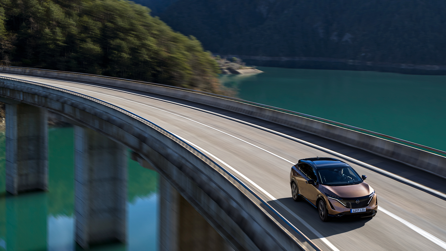 Nissan ARIYA in Fahrt über eine Brücke.
