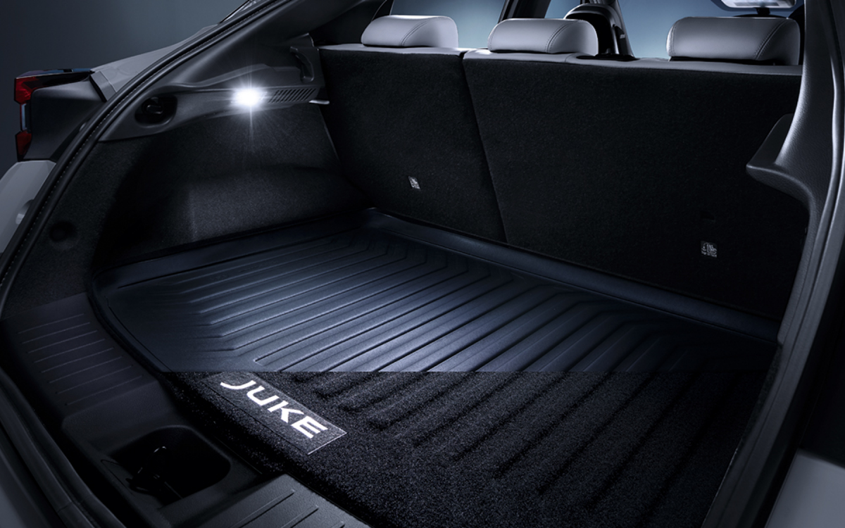 Variabler Kofferraumboden im Kofferraum eines Nissan Juke montiert – ein Laptop und eine Kamera darunterliegend.