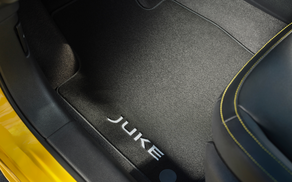 Velours-Fußmatte mit Juke Schriftzug auf der Fahrerseite in einem gelben Nissan Juke.