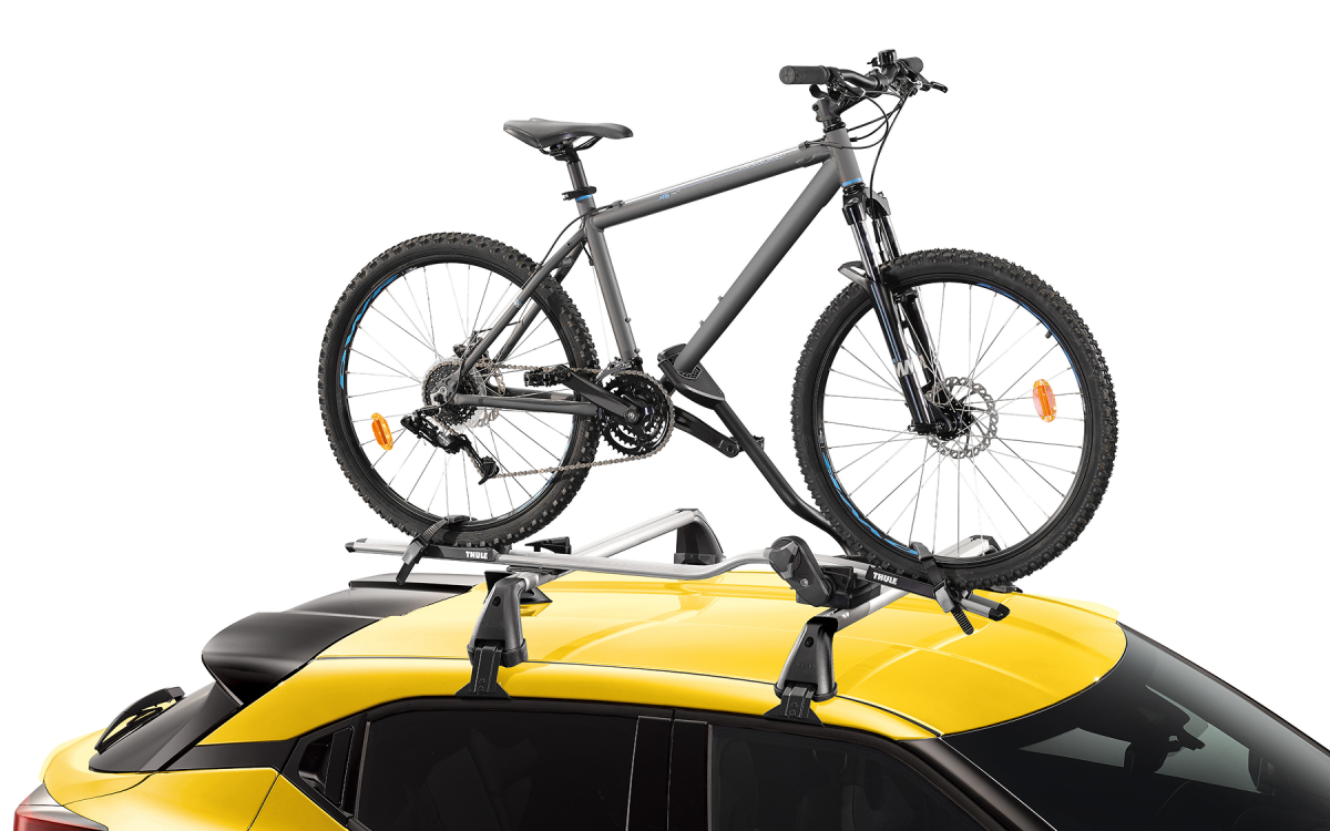 Fahrradträger mit Fahrrad auf dem Dach eines gelben Nissan Juke montiert.