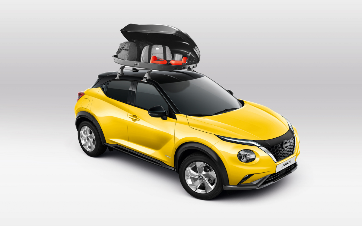 Beladene Dachbox auf dem Dach eines gelben Nissan Juke montiert.