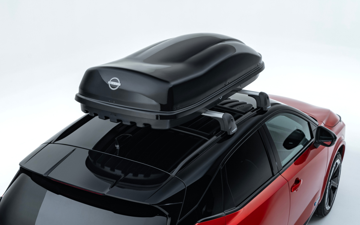 Schwarze Dachbox auf dem Dach eines roten Nissan Qashqai montiert.