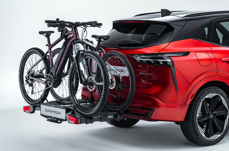 Fahrradträger mit zwei Fahrrädern am Heck eines roten Nissan Qashqai montiert.