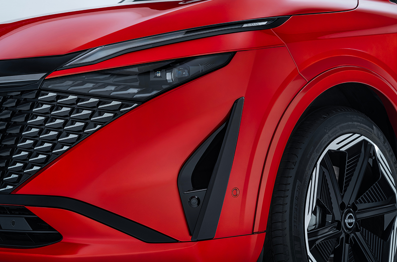 Frontansicht eines roten Nissan Qashqai mit Detailansicht des linken Frontscheinwerfers und Designelementen.