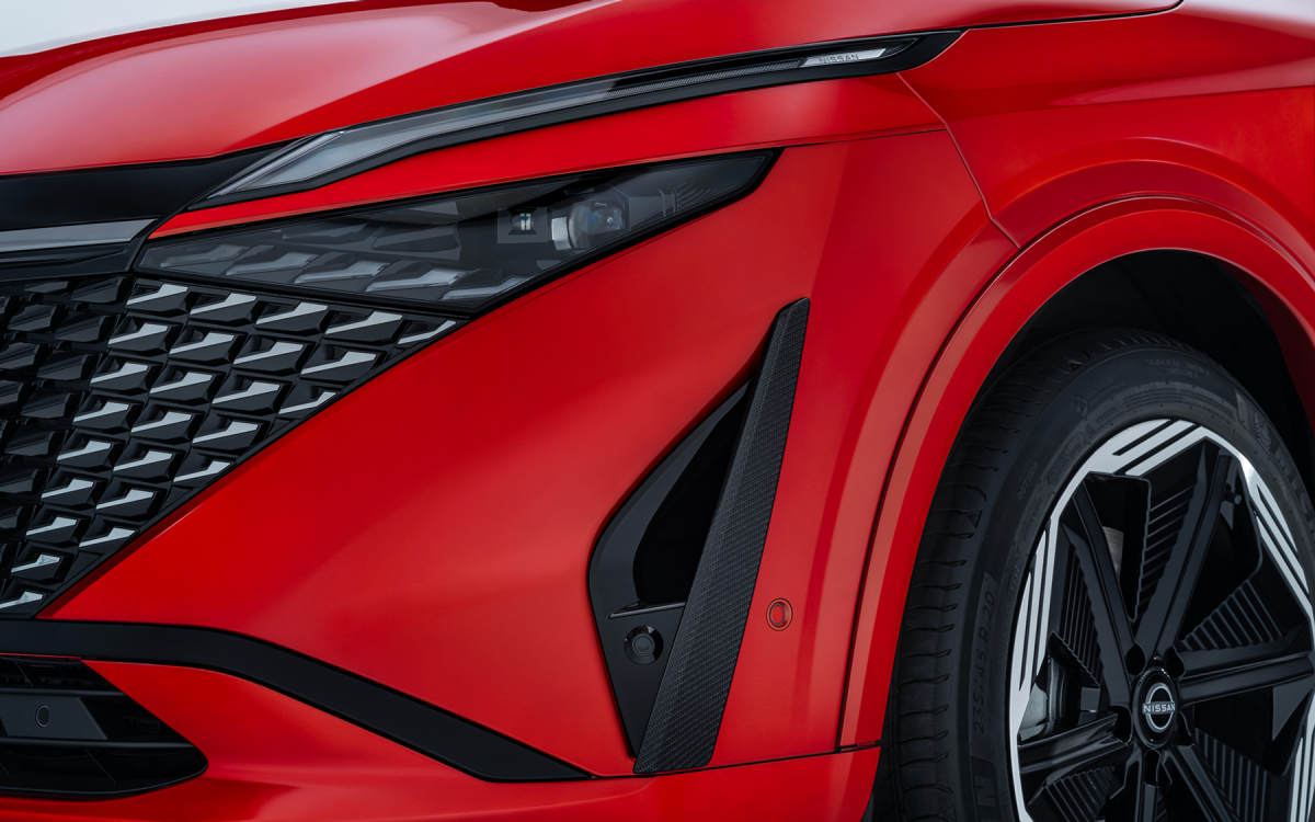 Frontansicht eines roten Nissan Qashqai mit Detailansicht des linken Frontscheinwerfers und Designelementen.