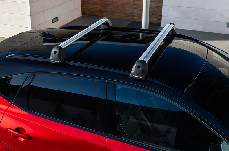 Silberne Querträger auf dem Dach eines roten Nissan Qashqai montiert.