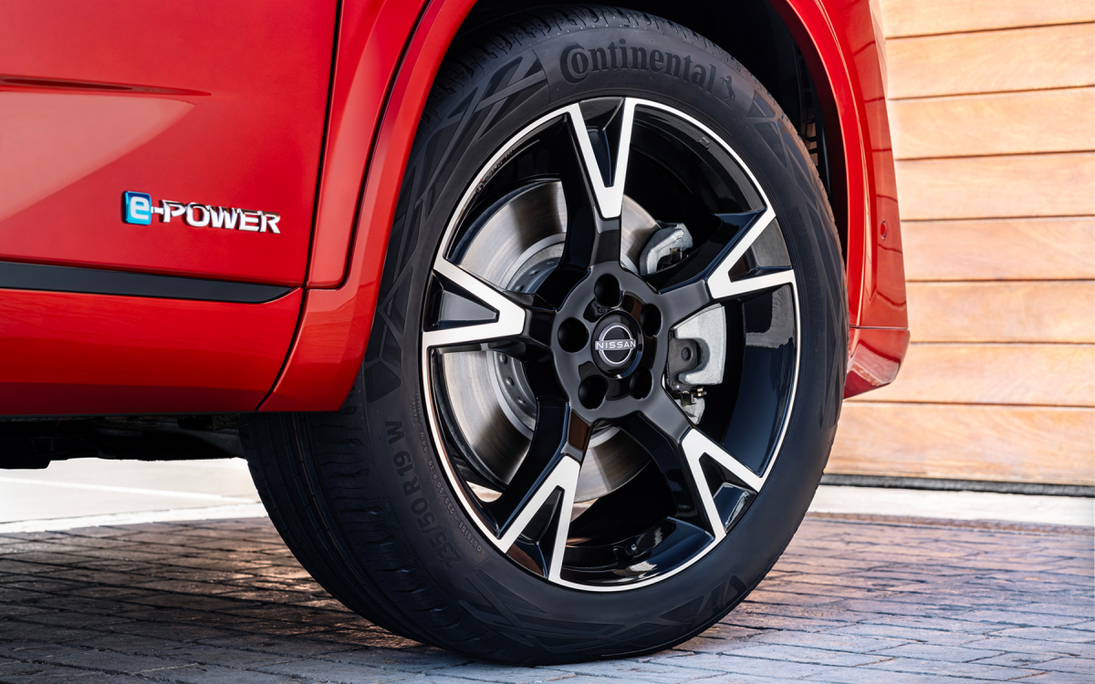 Silberne Winter-Leichtmetallfelge mit Reifen montiert an einem roten Nissan Qashqai.