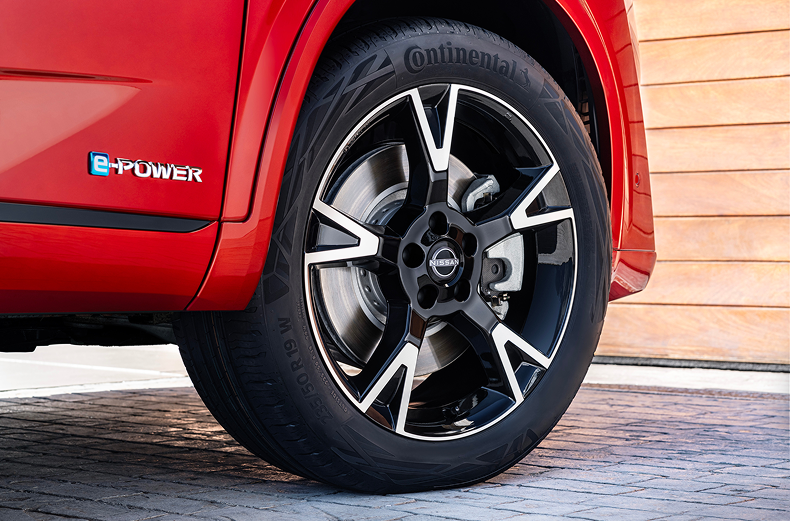 Silberne Winter-Leichtmetallfelge mit Reifen montiert an einem roten Nissan Qashqai.