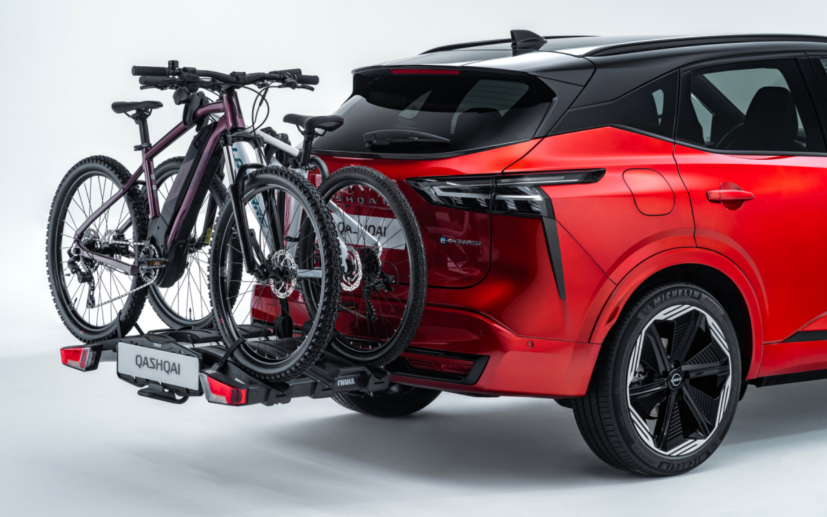 Fahrradträger mit zwei Fahrrädern am Heck eines roten Nissan Qashqai montiert.