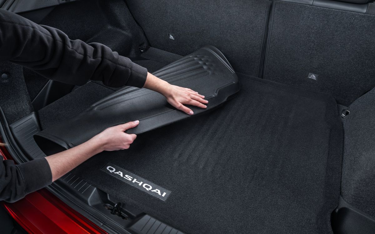 Wendbare Kofferraumwanne, die im Kofferraum eines roten Nissan Qashqai umgeschlagen wird – sowohl Gummiseite als auch Veloursseite sichtbar.