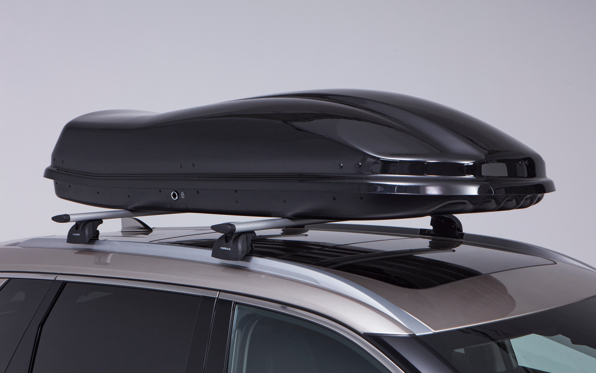 Schwarze Dachbox auf dem Dach eines Nissan X-Trail montiert.