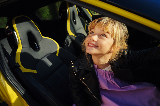 Lächelndes Mädchen steigt vom Beifahrersitz eines gelben Nissan Juke aus.