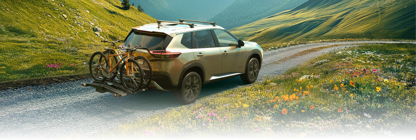 Nissan X-Trail mit beladenem Fahrradträger fährt durch eine farbenfrohe Frühlingslandschaft.