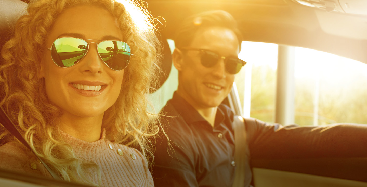 Mann und Frau lächelnd mit Sonnenbrille im Auto
