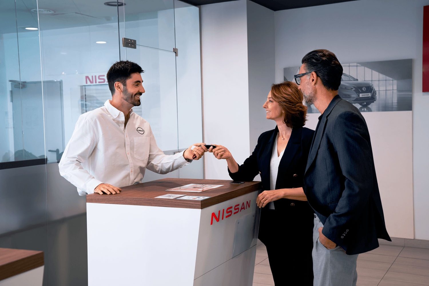 Asesor comercial entregando llaves coche Nissan a una pareja