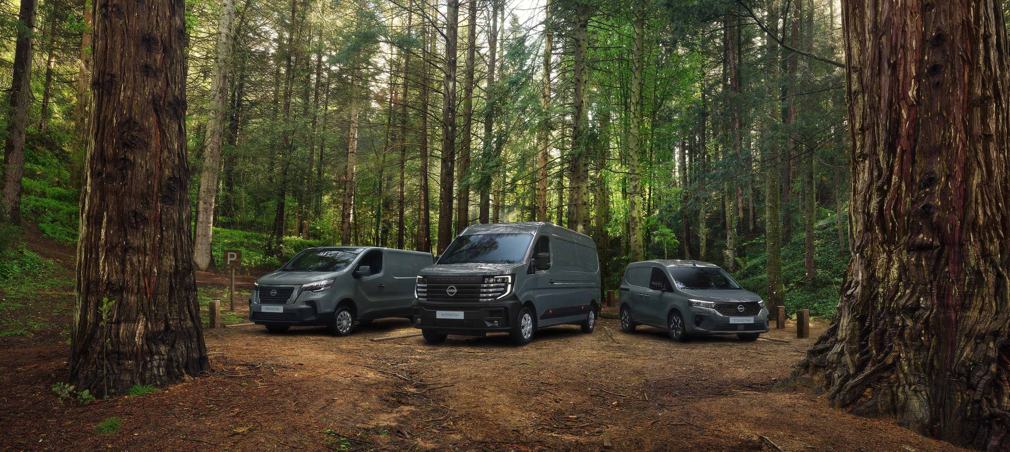 Gama de vehículos comerciales Nissan estacionados en un bosque.