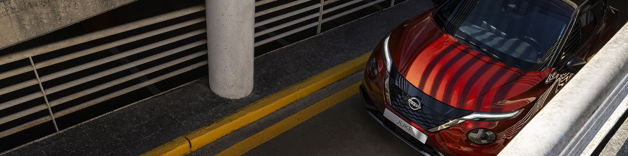 Nissan Juke híbrido amarillo circulando por ciudad con mujer pasando por paso de peatones