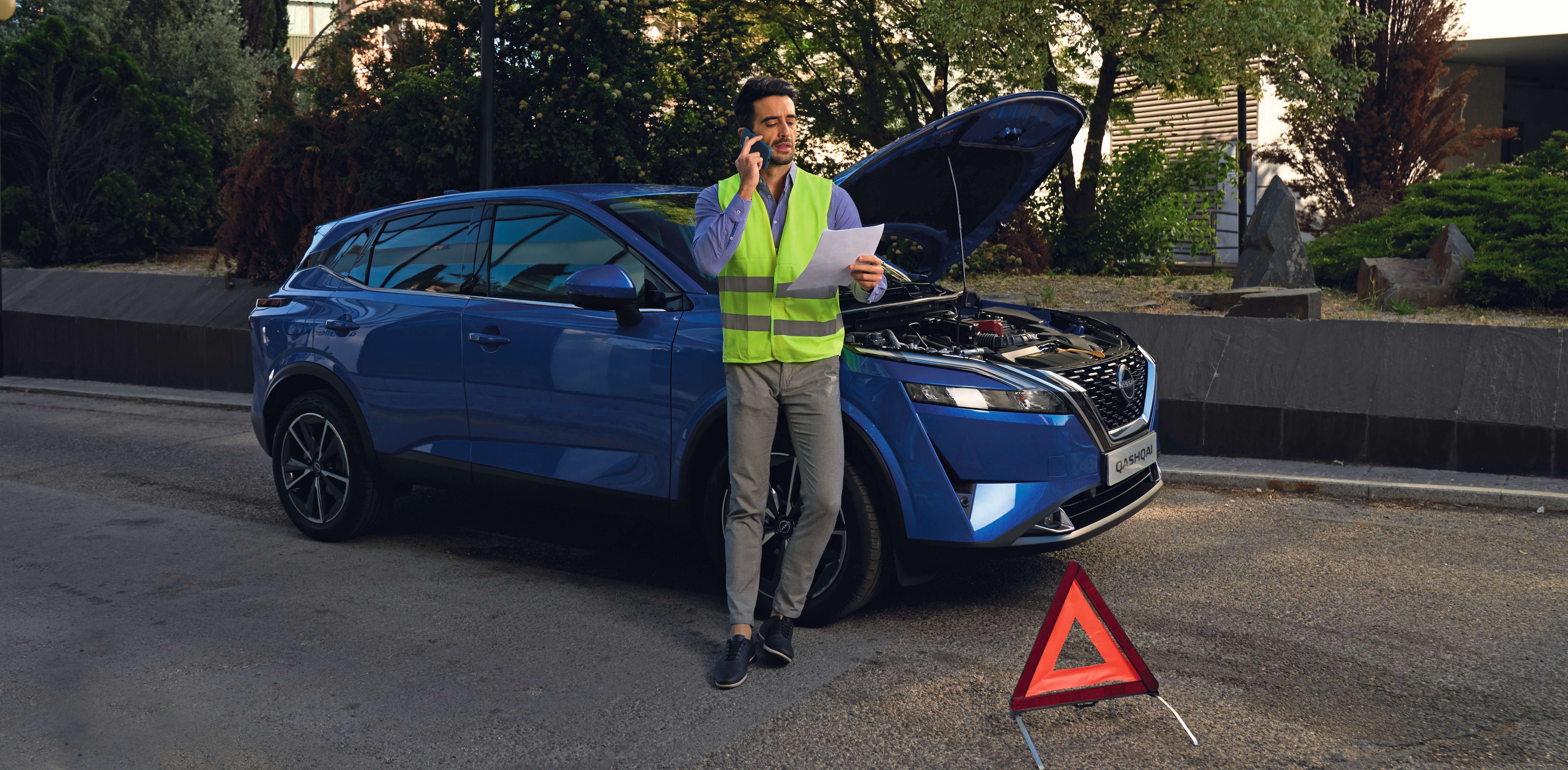 Hombre llamando a asistencia junto a su Nissan Qashqai azul