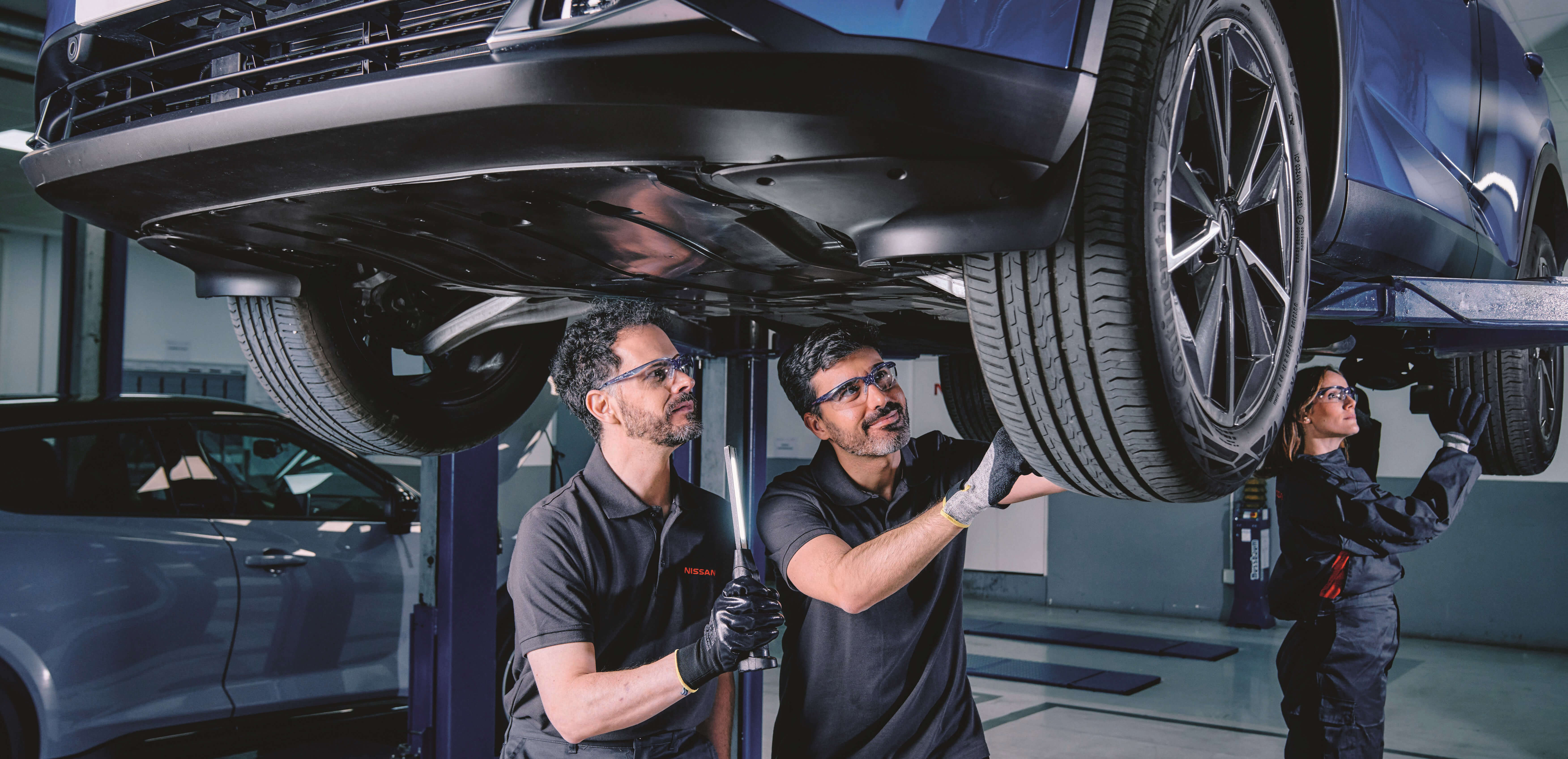 3 mecánicos Nissan revisando los neumáticos de un Nissan