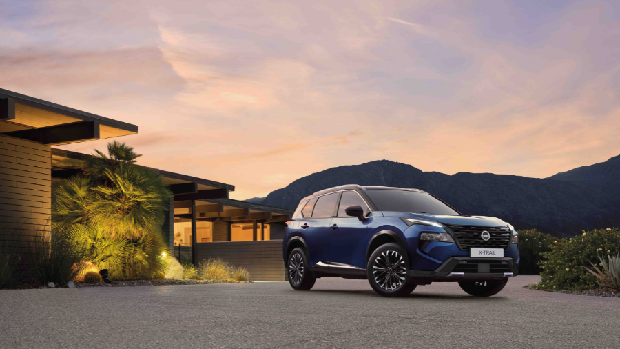 Nissan X-Trail e-POWER con montañas y casa de fondo