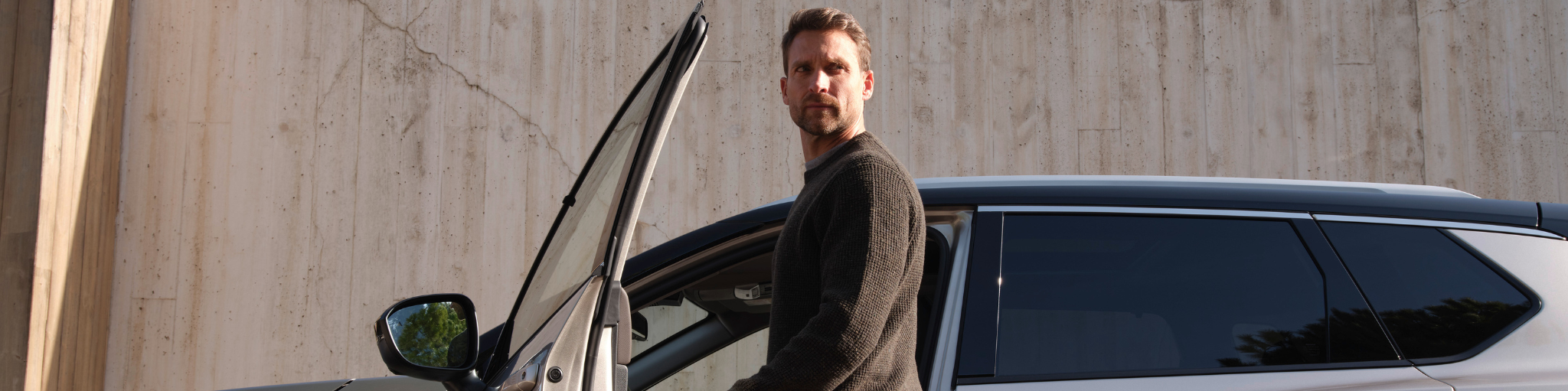 Hombre posando junto a un Nissan con la puerta abierta
