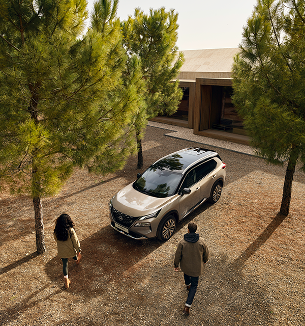 Pareja junto a un Nissan X-Trail aparado frente una casa