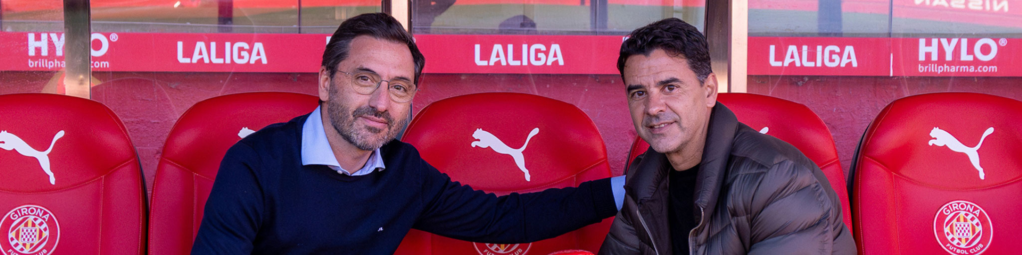 Imagen aumentada de dos personas sentadas en un banquillo de un campo de fútbol