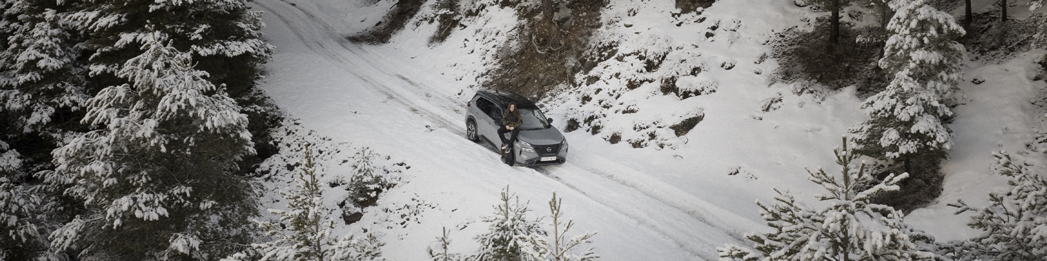 Un vehículo Nissan estacionado en un camino de nieve junto a Lethal Crisis
