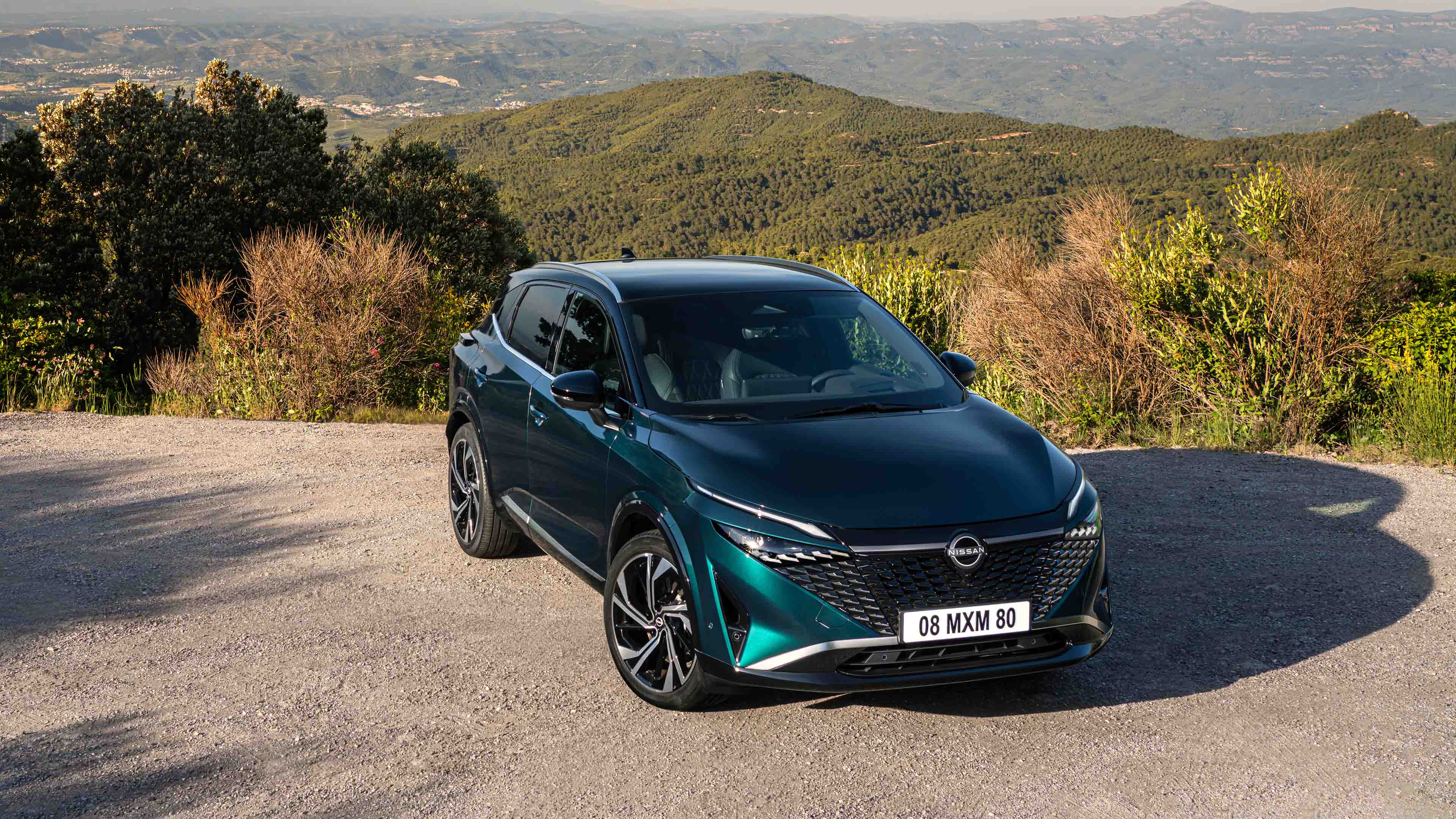 Nissan Qashqai e-Power verde oscuro estacionado en paisaje natural